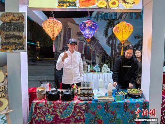 邓保罗(左一)在自己的摊位上推广南洋特色美食。 中新网记者 钟升 摄 邓保罗(左一)在自己的摊位上推广南洋特色美食。 中新网记者 钟升 摄