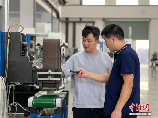 郭奕廷(左)和工人探讨设备细节。中新网记者 朱晓颖 摄 郭奕廷(左)和工人探讨设备细节。中新网记者 朱晓颖 摄
