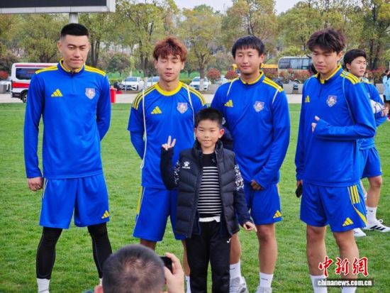 4月1日，孩子们踏入绿茵场，观摩“苏超”南京队训练，并和队员们互动。　中新社记者 泱波 摄