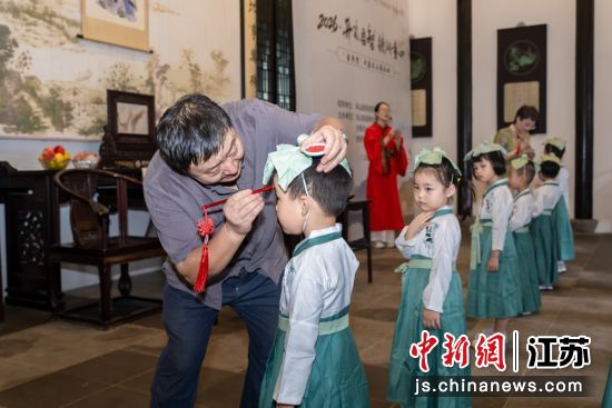 启蒙老师手持朱砂笔为孩童点“红痣”。鸿山街道 供图 启蒙老师手持朱砂笔为孩童点“红痣”。鸿山街道 供图