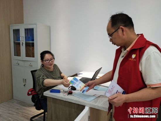 社区工作人员协同志愿者向居民发放宣传资料,讲解《长江保护法》的重点内容。