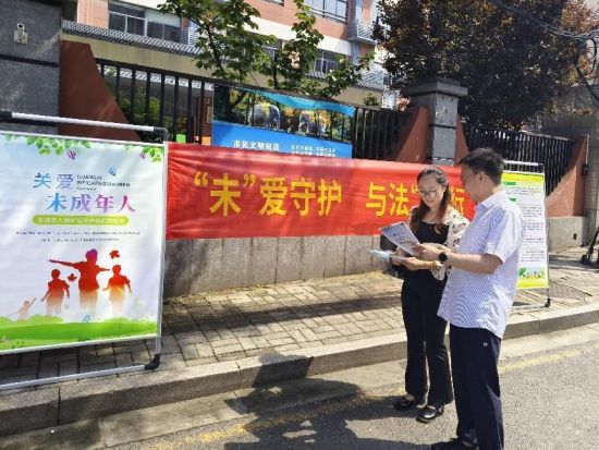 三分局普法人员在学校门口向未成年人及其家长普法。