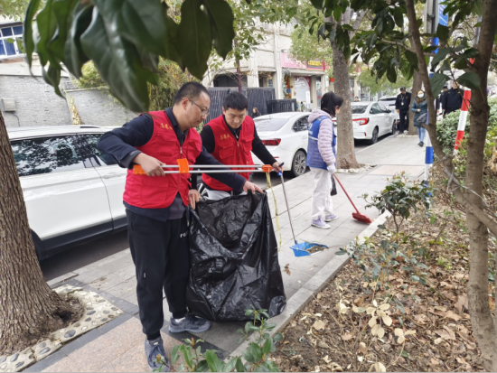 图为红叶志愿者在清理街路两侧绿化带内的落叶。南京烟草三分局供图
