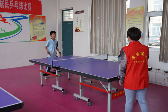 志愿者陪学生打乒乓球。
