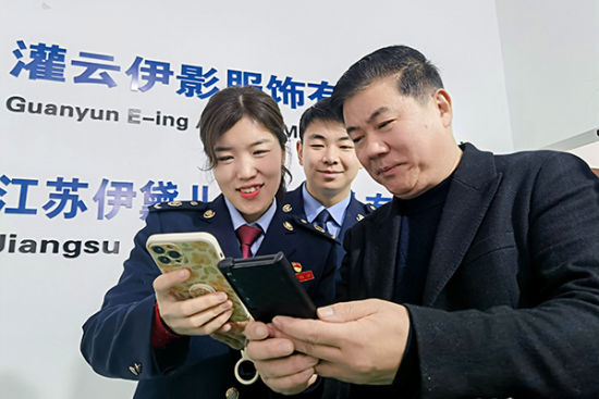 国家税务总局灌云县税务局工作人员与企业职工交谈。